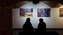 Silhouettes of people seated looking at the exhibition. 