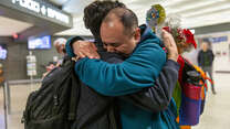 Two men hugging while having a reunification at the airport. 