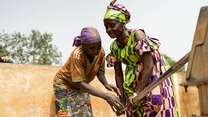 Andrienne helps her sister-in-law Hortense use the well, where access to safe water is helping families stay healthier and easing the burden of daily life.