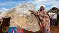 A woman works on improving her makeshift shelter in Somalia.