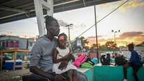A displaced father sits with his daughter in Haiti.