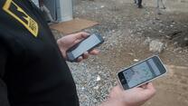 An IRC aid worker in Greece looks at an IRC  shelter mapping app on a smartphone