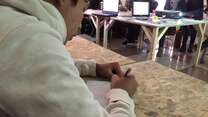 A refugee child in a sweatshirt writes an assignment in a classroom in Belgrade