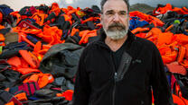 Mandy Patinkin in Greece, with a mountain of refugees' lifejackets