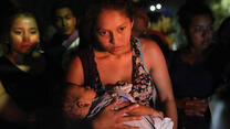 A refugee women holding a baby in a crowd as she seeks asylum in Mexico 