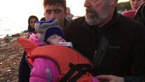 Mandy Patinkin carries Masuma, a young Afghan refugee onto a Greek beach 