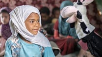 Young girl smiles at a cow puppet