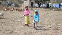 Two young girls hold hands in a field in Yemen