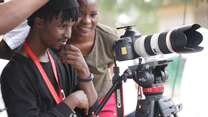 Film makers Amina and Abdul looking down a camera.