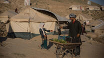 Man hands something to a girl at a Afghanistan crisis camp for drought displaced people right outside Qala-e-Naw, Badghis province.  