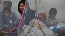 A women sat in a tent with children.