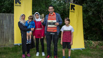 IRC client Khalil holds his RISE certificate and smiles with his wife and children.