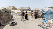 A family walk through a makeshift camp in Yemen.
