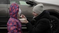 A woman spooning food into a child's mouth