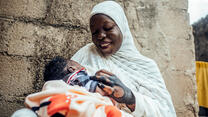 IRC client Hussiena Ibrahim smiles at 7 day old Bello.