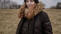 A woman wearing a black coat standing in a field