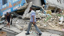 A man and woman walk gingerly past the rubble of buildings in Port-au-Prince, Haiti destroyed by the powerful 2010 earthquake. 