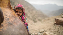 A young girl wearing a pink floral headscarf in a remote mountain area of Yemen