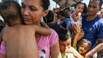 A family fleeing violence in Honduras waits to cross into Mexico on their way to seek asylum in the U.S. 