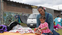 Carina plays with her daughter Kimberly in her lap, camped alongside other Venezuelan refugees