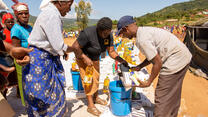 A woman collects food and emergency aid from IRC staff in Zimbabwe after Cyclone Idai