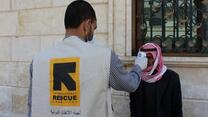 An IRC health worker scans a man in Syria for fever