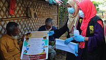Two IRC community health workers post COVID-19 awareness posters