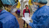 IRC health workers in PPE admit socially distanced patients wearing face masks to their clinic on the Venezuela/Colombia border.