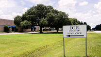 A lawn with a black and white sign that says "ICE Courts Entrance"
