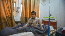 A boy sits up in his hospital bed in Syria.
