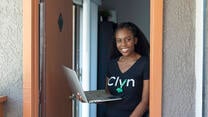Diana Muturia, founder of the app Clyn, standing in a doorway and holding her laptop