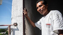 Reynaldo, a Salvadoran man who works as a painter, stands in the doorway of a church in El Salvador.