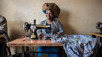 Domitila Kaliya, a Congolese refugee, smiles as she sits at her sewing machine