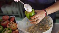 A woman stuffs a pepper with filling.