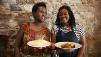 Two women smiling and holding plates of food.