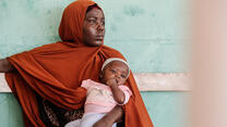 A mother sits holds her baby at an IRC health clinic in Somalia