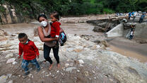 A woman with two kids manages to walk across the destroyed bridge over Higuito river on November 19, 2020 in Copan, Honduras, after Hurricane Iota.
