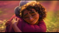 A screenshot from Disney's animated film Encanto. Mirabel, who has curly hair and wears glasses, hugs her Abuela, who has grey hair in a bun and a pink shirt. 