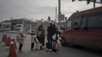 A Ukrainian family embraces at a Ukraine-Poland border crossing next to a van.