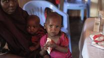 A Somali toddler sits eating specially nutritious peanut paste from a packet at an IRC health center that diagnoses and treats severe acute malnutrition.