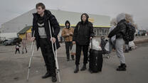 A teenage boy using crutches waits at a refugee center in Poland with other people who fled Russian attacks in Ukraine. 