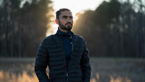 Photojournalist Mohammad Anwar Danishyar stands in front of a forest in the evening. 