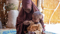 A mother in Niger sits on a mat feeding her baby, who is being monitored by the IRC for signs of malnutrition.