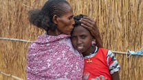 A mother kisses and holds the head of her son.