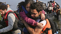 A Syrian man carries a little girl onto a Greek beach after arriving in a small boat from Turkey.