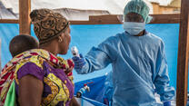 A health workers uses a scanner to screen a woman and baby for signs of Ebola