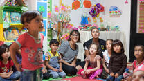 Rashida Jones sits with a small group of children at an IRC Safe Healing and Learning Space for young Syrian refugees in Lebanon.