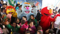 Children playing with life size Sesame Street characters.