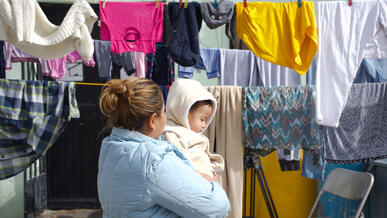 A Guatemalan mother stands holding her baby amid laundry hanging out to dry in Ciudad Juárez, Mexico.