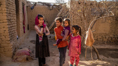 Four girls pose for a photo in an outdoors courtyard.